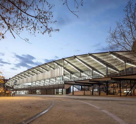Fachada del Canòdrom iluminada al atardecer, destacando su arquitectura moderna