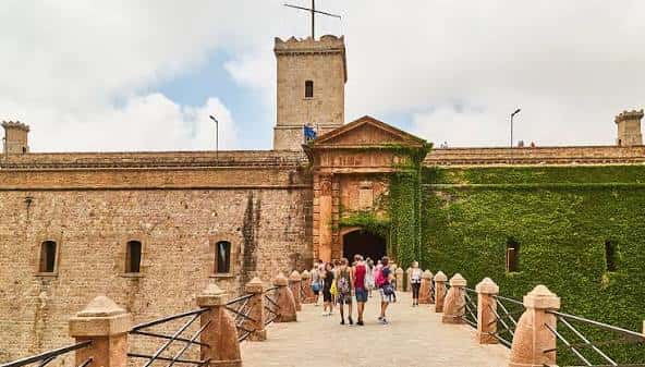 Entrada principal del castillo con el puente de acceso y turistas caminando
