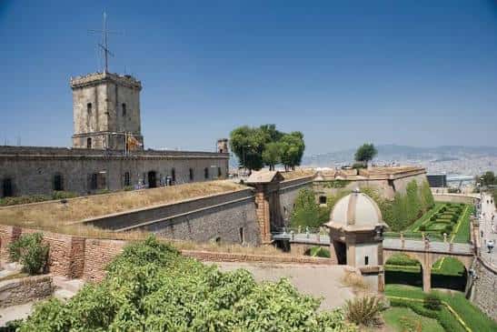 Vista lateral del castillo mostrando la torre principal y los jardines de la entrada