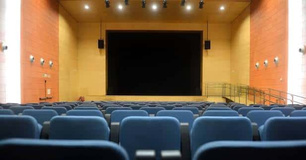 Interior del auditorio con butacas azules y escenario listo para eventos