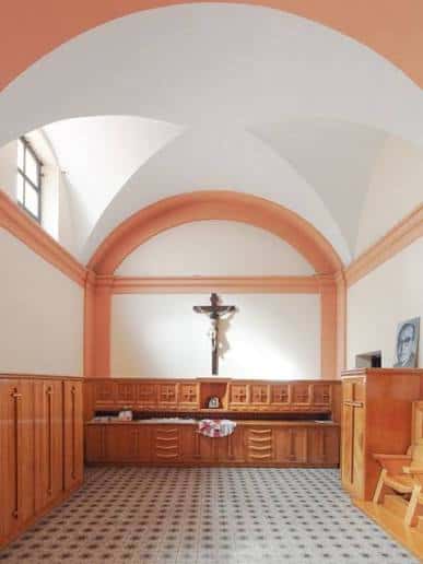 Interior de la capilla con crucifijo y bancos de madera