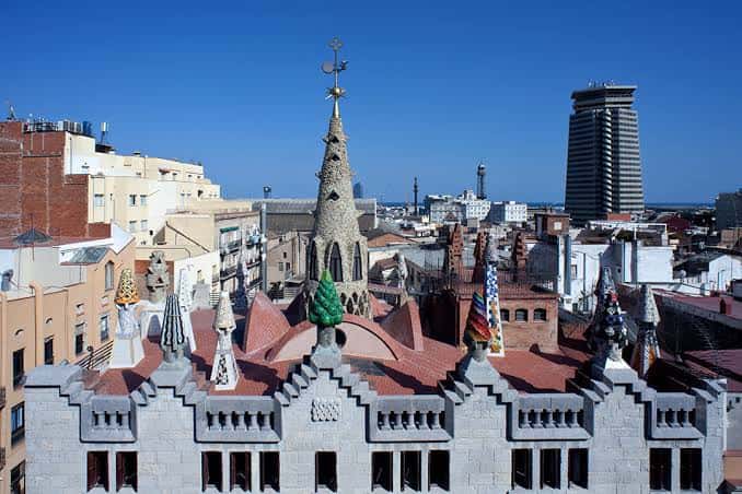 Vista panorámica de la azotea del Palau Güell con chimeneas de mosaico y la ciudad de Barcelona al fondo