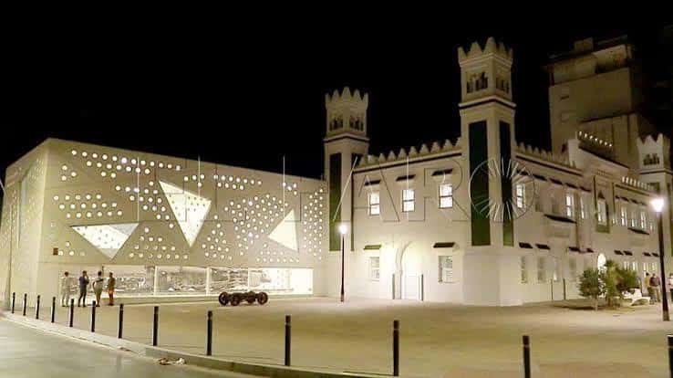 Vista nocturna del Centro Cultural de la Estación de Ferrocarril en Ceuta, mostrando su fachada moderna con iluminación y torres históricas