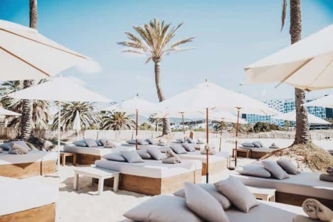 Playa del Beachouse Ibiza con tumbonas y sombrillas blancas