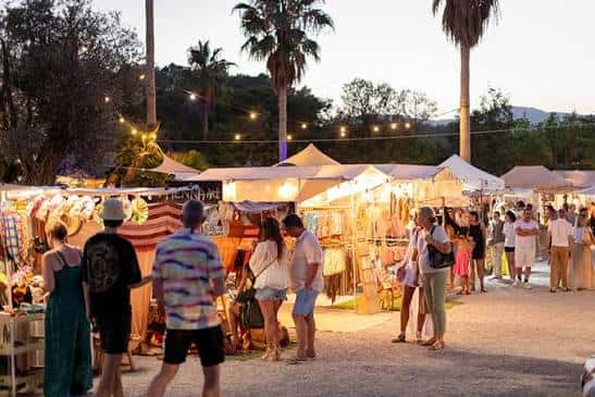 Vista del mercadillo Las Dalias al atardecer con puestos iluminados y visitantes