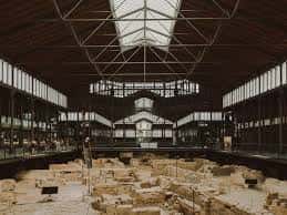 Vista interior del Museo de Historia de Barcelona con ruinas arqueológicas bajo una estructura de hierro y cristal