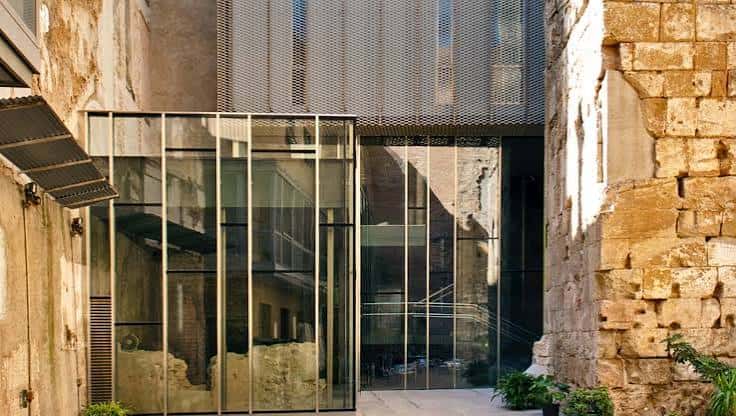 Fachada de vidrio y piedra que combina arquitectura antigua y contemporánea