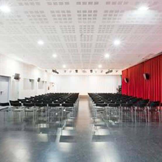 Sala de eventos interior con butacas negras y cortinas rojas