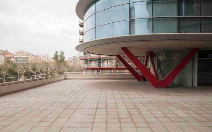 Vista exterior del edificio moderno con fachada de cristal y estructura roja