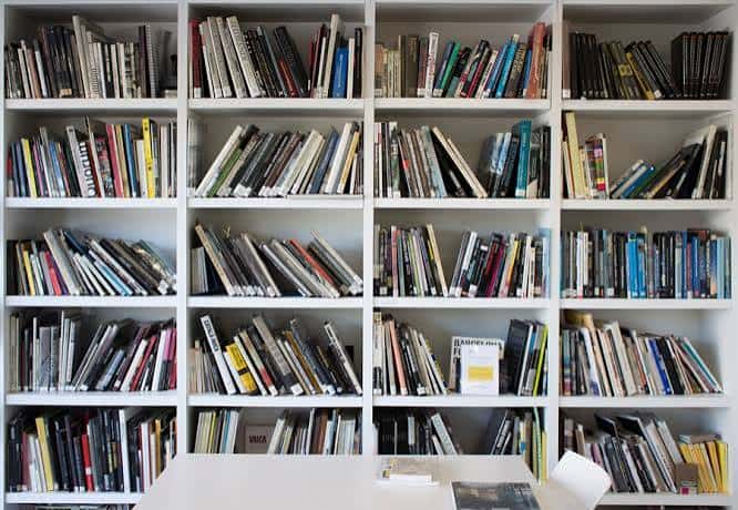 Interior con estanterías blancas llenas de libros y revistas de fotografía