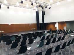 Interior del auditorio con escenario y butacas dispuestas para eventos culturales