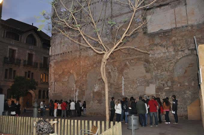 Grupo de personas reunidas en la plaza junto a las ruinas históricas