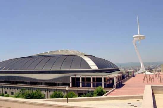 Vista exterior del Palau Sant Jordi con su característica cúpula y la Torre de Communications al fondo
