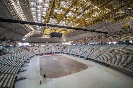 Interior del recinto vacío mostrando la estructura metálica del techo y las gradas