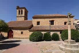 Vista exterior de la Iglesia de Pizarrales con su fachada de piedra y campanario bajo un cielo azul