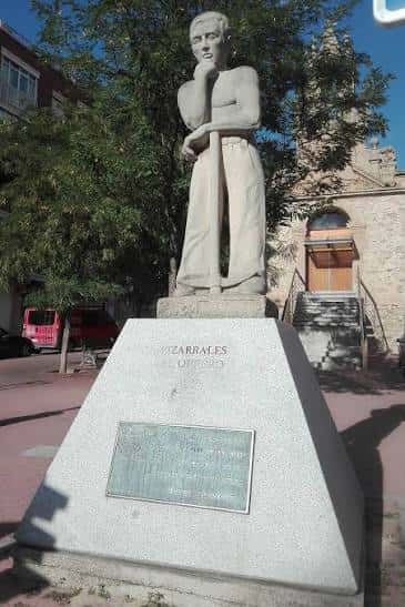 Monumento al Obrero en la Plaza de la Iglesia de Pizarrales, con la iglesia al fondo
