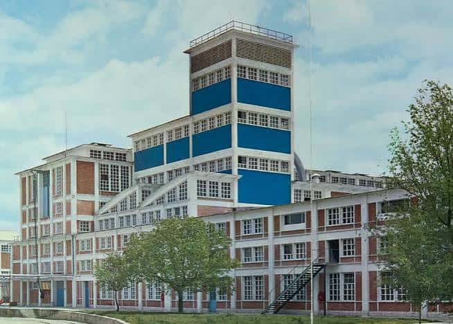 Vista exterior de la antigua Fábrica GAL en Alcalá de Henares, destacando su arquitectura industrial con fachada de ladrillo y torre azul