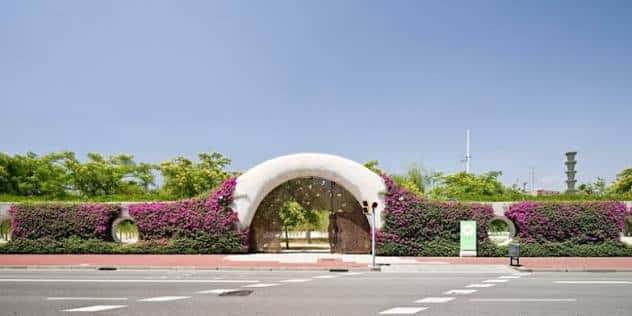 Entrada principal del parque con un arco blanco cubierto de flores moradas