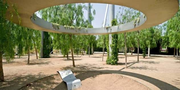 Área sombreada del parque con árboles y una estructura circular de hormigón