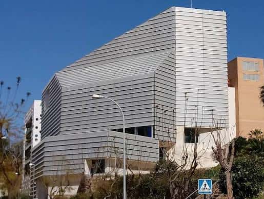 Vista exterior de la Biblioteca Pública Adolfo Suárez en Ceuta con fachada moderna de paneles metálicos bajo cielo azul
