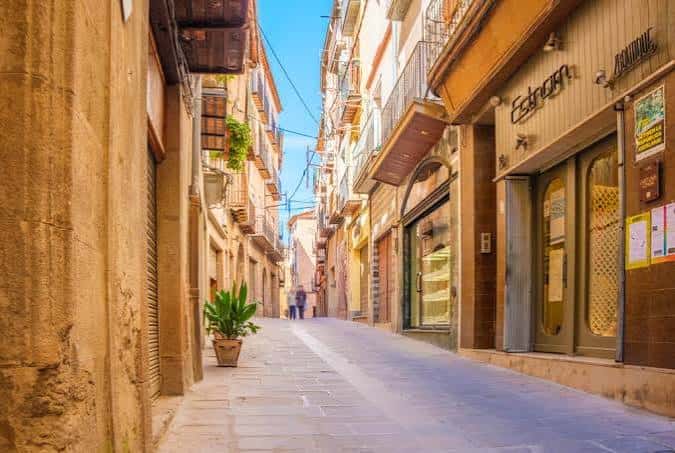 Callejón estrecho con edificios de piedra y tiendas tradicionales