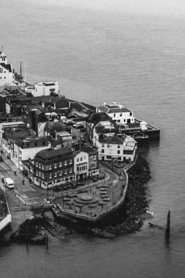 Vista aérea histórica en blanco y negro del puerto de Portsmouth, destacando la ubicación costera del The Sally Port Inn