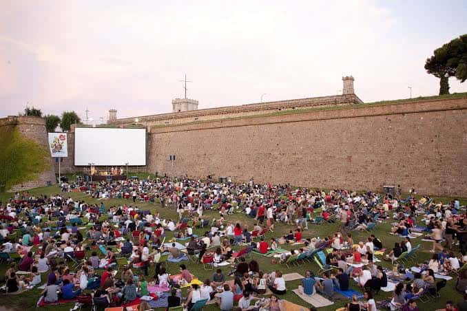 Vista general del cine al aire libre en la muralla de Montjuïc con público sentado en la hierba