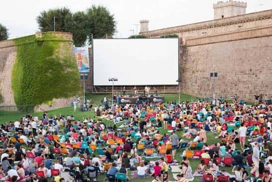 Público disfrutando de una función en la Sala Montjuïc con sillas coloridas y pantalla grande