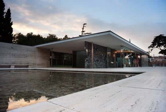Vista exterior del Pabellón Mies van der Rohe al atardecer con reflejo en la piscina