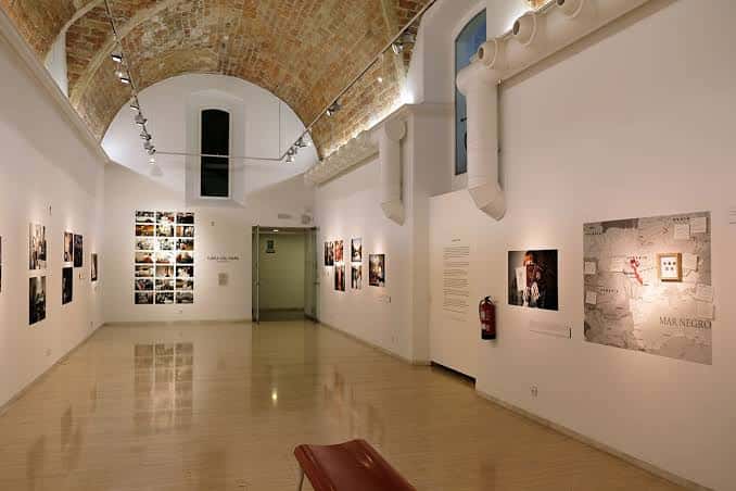 Espacio interior del centro cultural con techos abovedados y exposición fotográfica en curso