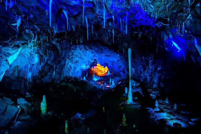 Interior de la cueva iluminado con luces azules y estalactitas