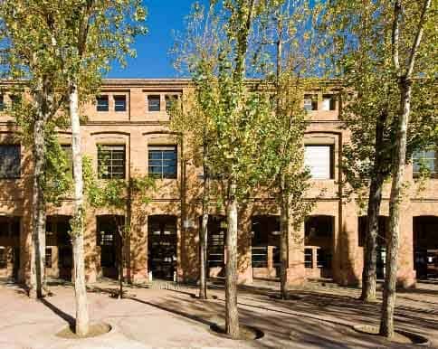 Fachada principal del edificio con arcos y árboles en primer plano