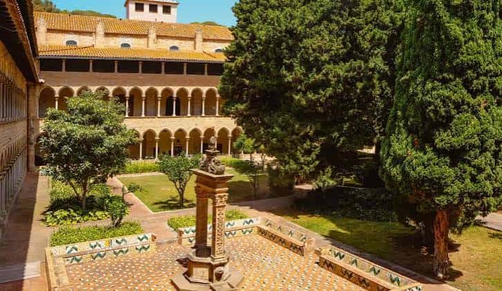 Claustro principal con fuente central y árboles frondosos bajo luz solar