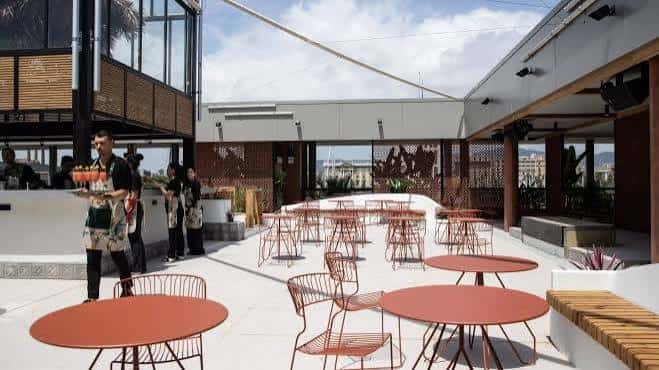 Zona de terraza exterior con mesas y personal del mercado