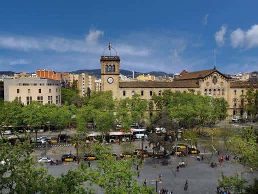 Vista panorámica de la fachada principal de la Universitat de Barcelona con su torre y plaza ajardinada