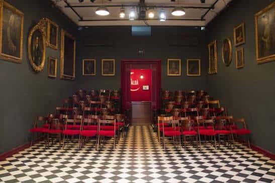 Vista general del interior del Teatre El Maldà con suelo de ajedrez y butacas rojas