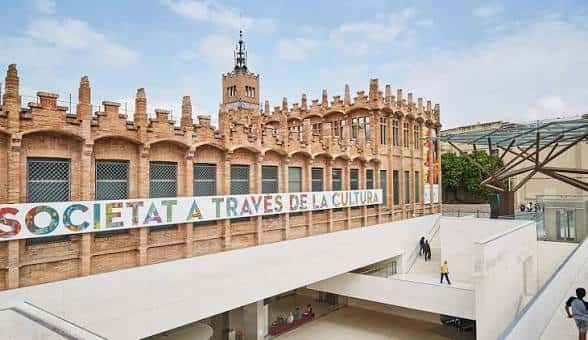 Vista lateral del CaixaForum Barcelona con el letrero 'SOCIETAT A TRAVÉS DE LA CULTURA' y la escalera de acceso