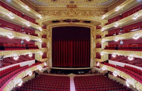 Interior del auditorio con cortina roja cerrada y balcones dorados iluminados