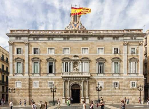 Fachada principal del Palau de la Generalitat con banderas ondeando y plaza concurrida