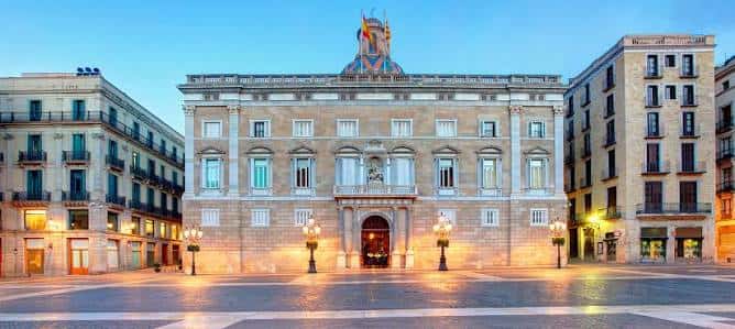 Fachada iluminada del Palau de la Generalitat al atardecer en la plaza