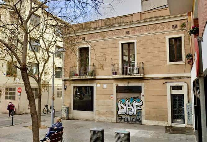 Fachada de un edificio en la plaza con grafitis y una persona sentada en un banco