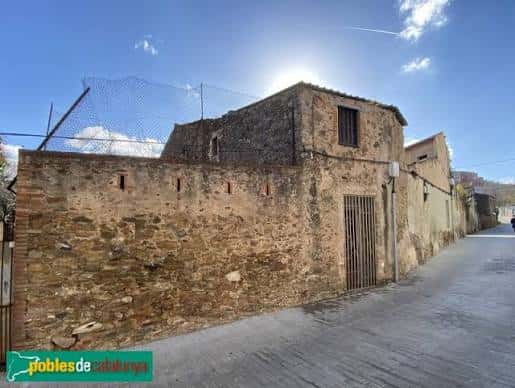 Fachada de piedra antigua en la calle Carrer d'Alarcón con cielo despejado