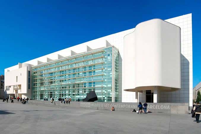 Vista exterior del MACBA con fachada blanca y cristalera bajo cielo azul