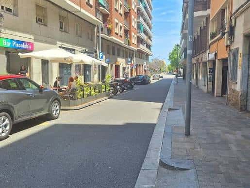 Vista de la calle Carrer de Garcilaso con terrazas de cafeterías y edificios residenciales