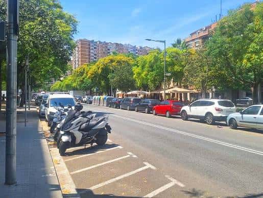 Calle Carrer de Garcilaso con árboles y vehículos estacionados