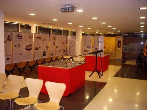 Interior del centro con mesas rojas y paneles expositivos, ideal para eventos culturales