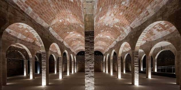 Interior con bóvedas de ladrillo y columnas iluminadas desde el suelo