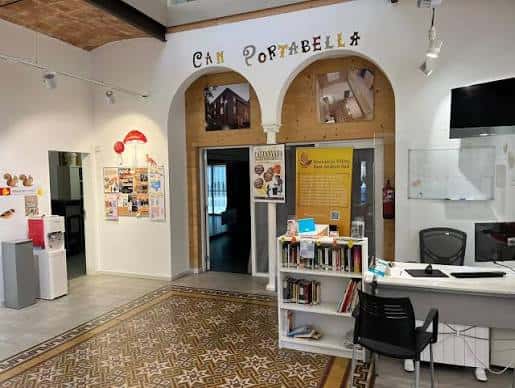 Interior del hall de recepción del Casal de Barri Can Portabella con decoración local y zona de información