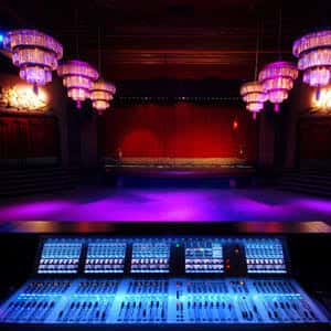 Vista desde la cabina de sonido hacia el escenario con luces púrpuras