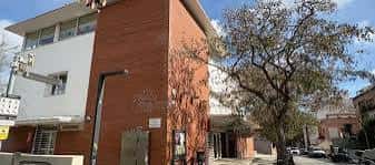 Entrada lateral del centro cívico con señalización y entorno urbano